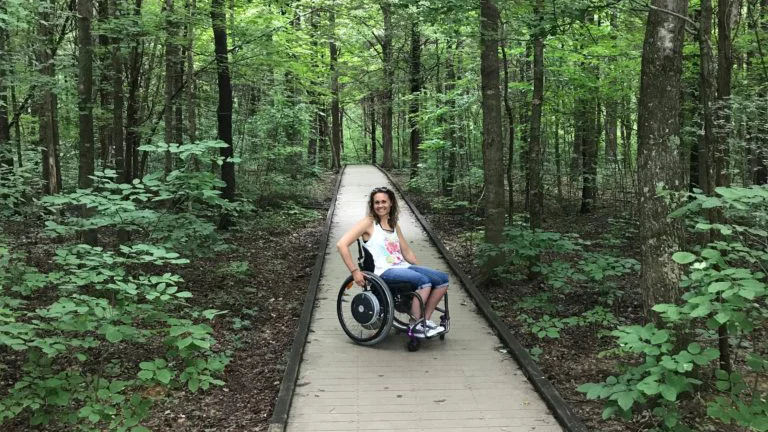 Arlene en silla de ruedas en un sendero en el bosque