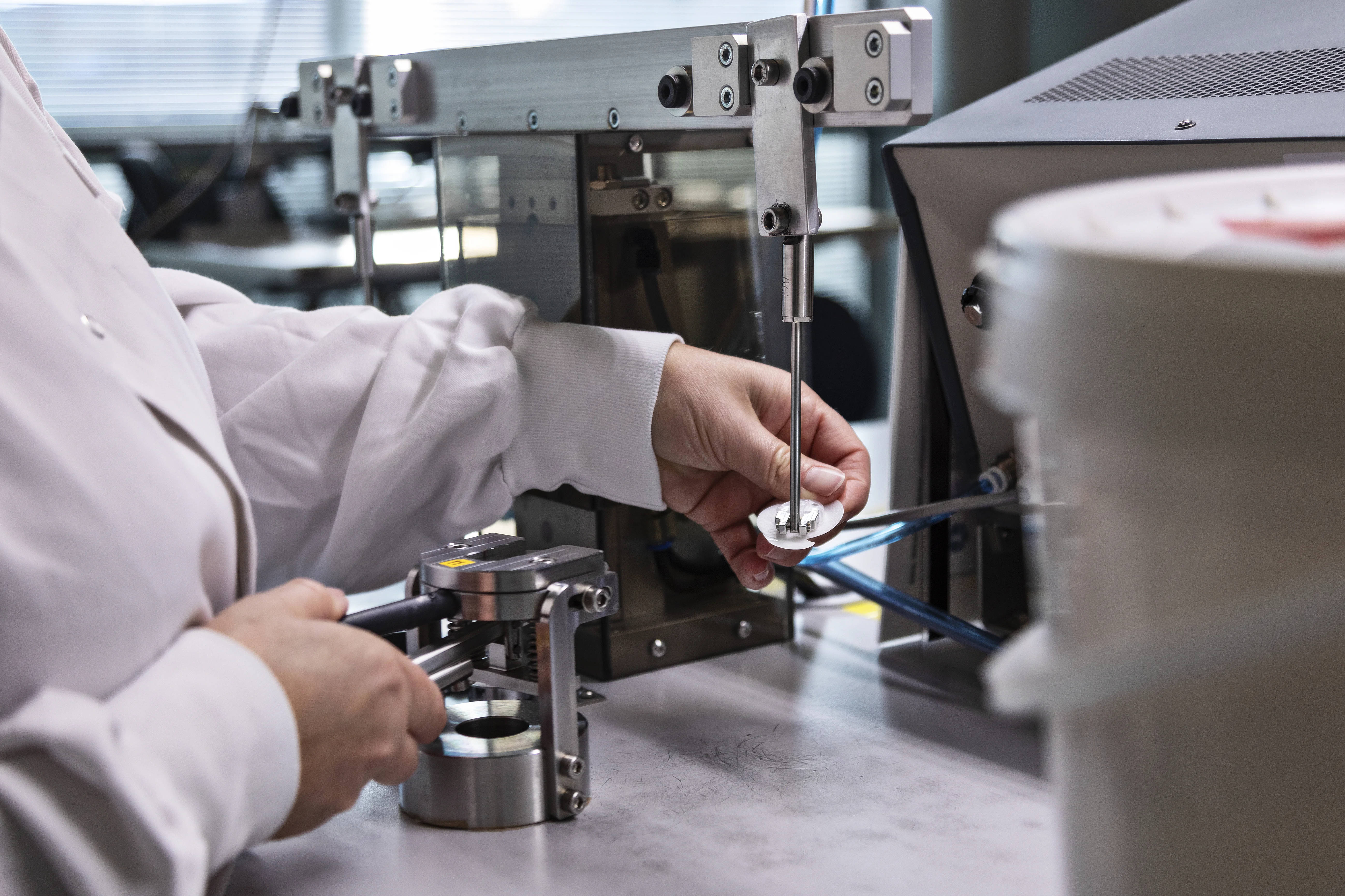 en person i en laboratoriefrakke, der arbejder på en maskine